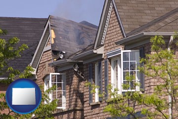house fire damage with a smoldering roof - with Colorado icon
