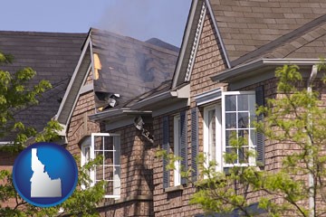 house fire damage with a smoldering roof - with Idaho icon
