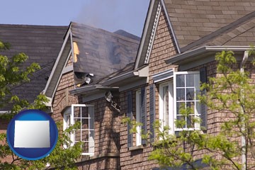 house fire damage with a smoldering roof - with Wyoming icon