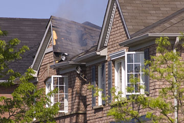 house fire damage with a smoldering roof